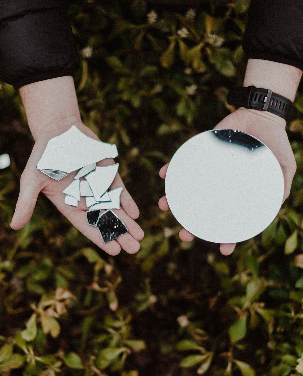 holding shattered mirror and intact mirror